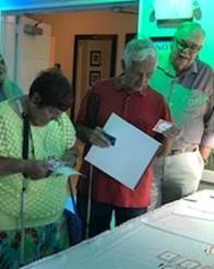 Volunteers Faye and John Hardin and Mike Lee check in to the Luncheon, receiving programs in print or braille