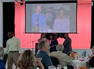 Handing out raffle prizes - and on the screen in the background, a slide show potpourri of previous luncheons, featuring recently retired Library Bureau Chief Jim Woolyhand